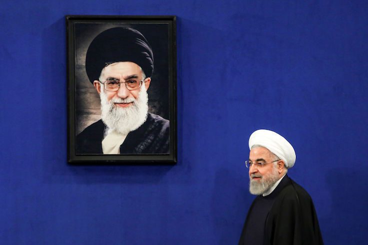 Iranian President Hassan Rouhani walks past a portrait of Supreme Leader Ayatollah Ali Khamenei