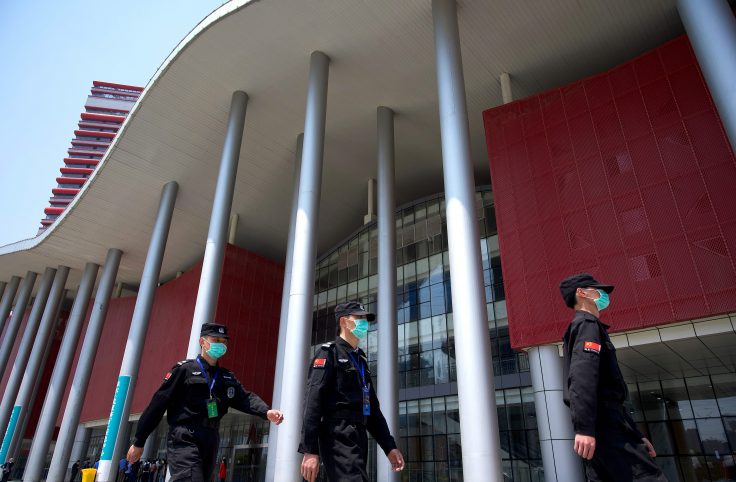 Security personnel wearing face masks walk in front of a field hospital in Wuhan