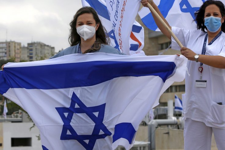 Medical professionals at Ziv Medical Centre wave Israeli national flags