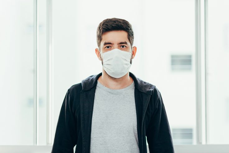 Portrait of man wearing surgical mask at home. Covid-19, coronavirus and quarantine concept.
